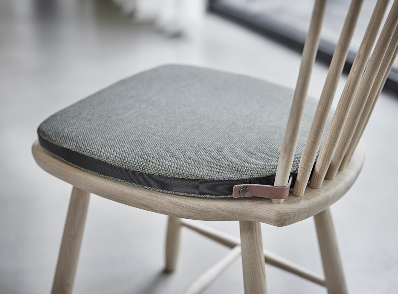 Lilla Åland stol med en Lilla Åland dyna i grått tyg med läderknäppning.