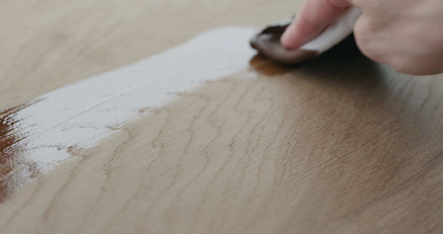 En hand oljar in trä med möbelolja för längre hållbarhet och skydd.